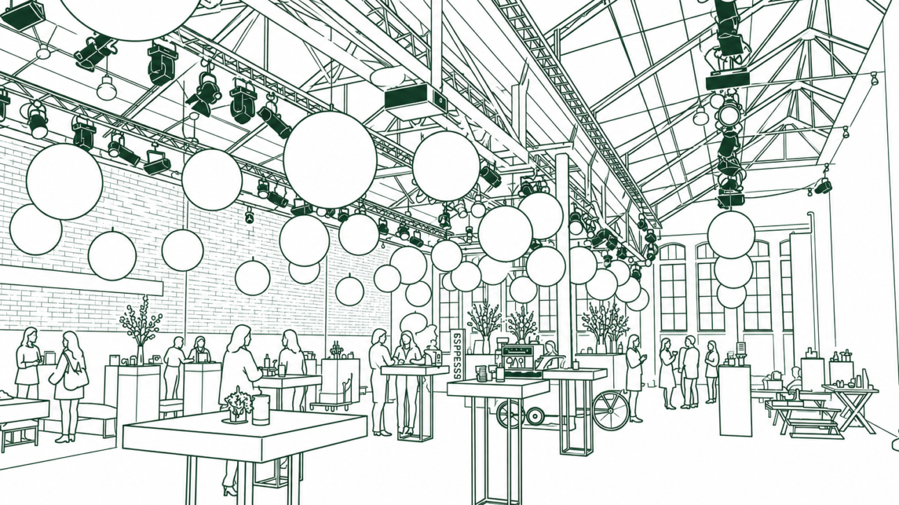 Indoor event space with hanging balloons, people mingling at tables and food stands in a large hall with an industrial ceiling.