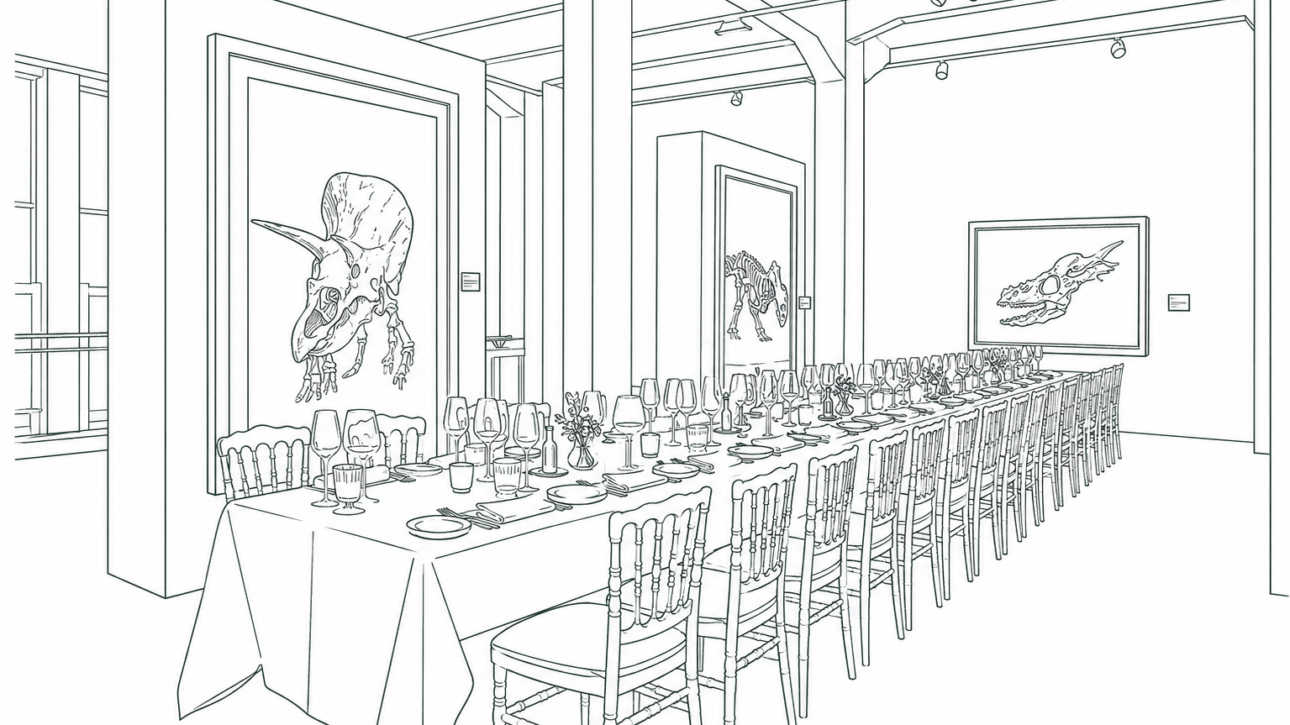 Long banquet table set for a formal dinner in a museum gallery, with numerous chairs, plates, glassware, and centerpieces, framed dinosaur artwork on the walls.